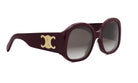A pair of burgundy-colored sunglasses with a gold-colored logo on the side.