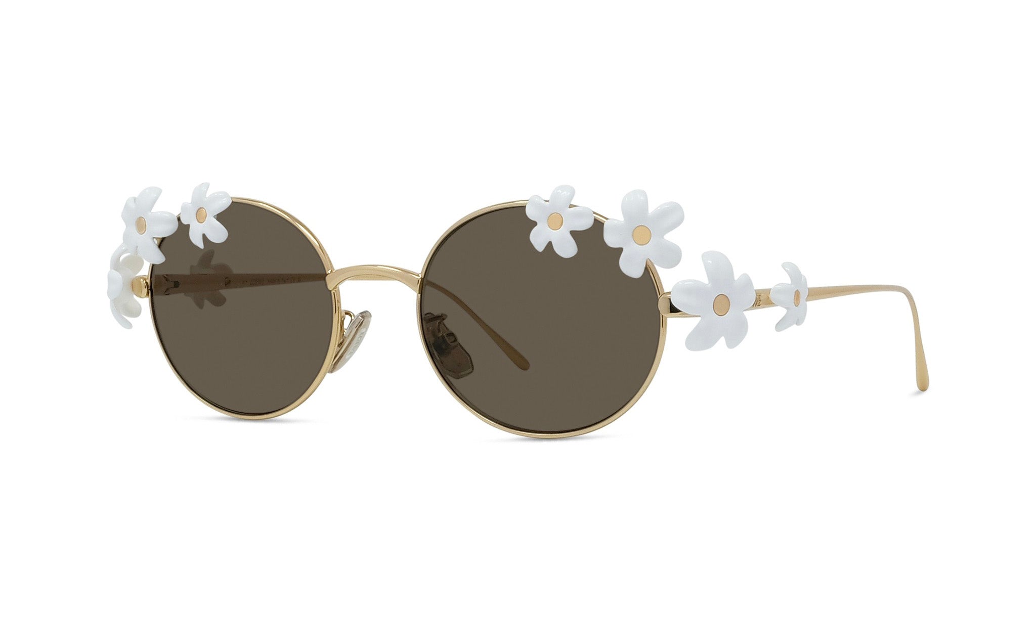 A pair of round sunglasses with a gold frame and dark lenses, adorned with white flower embellishments on the temples.