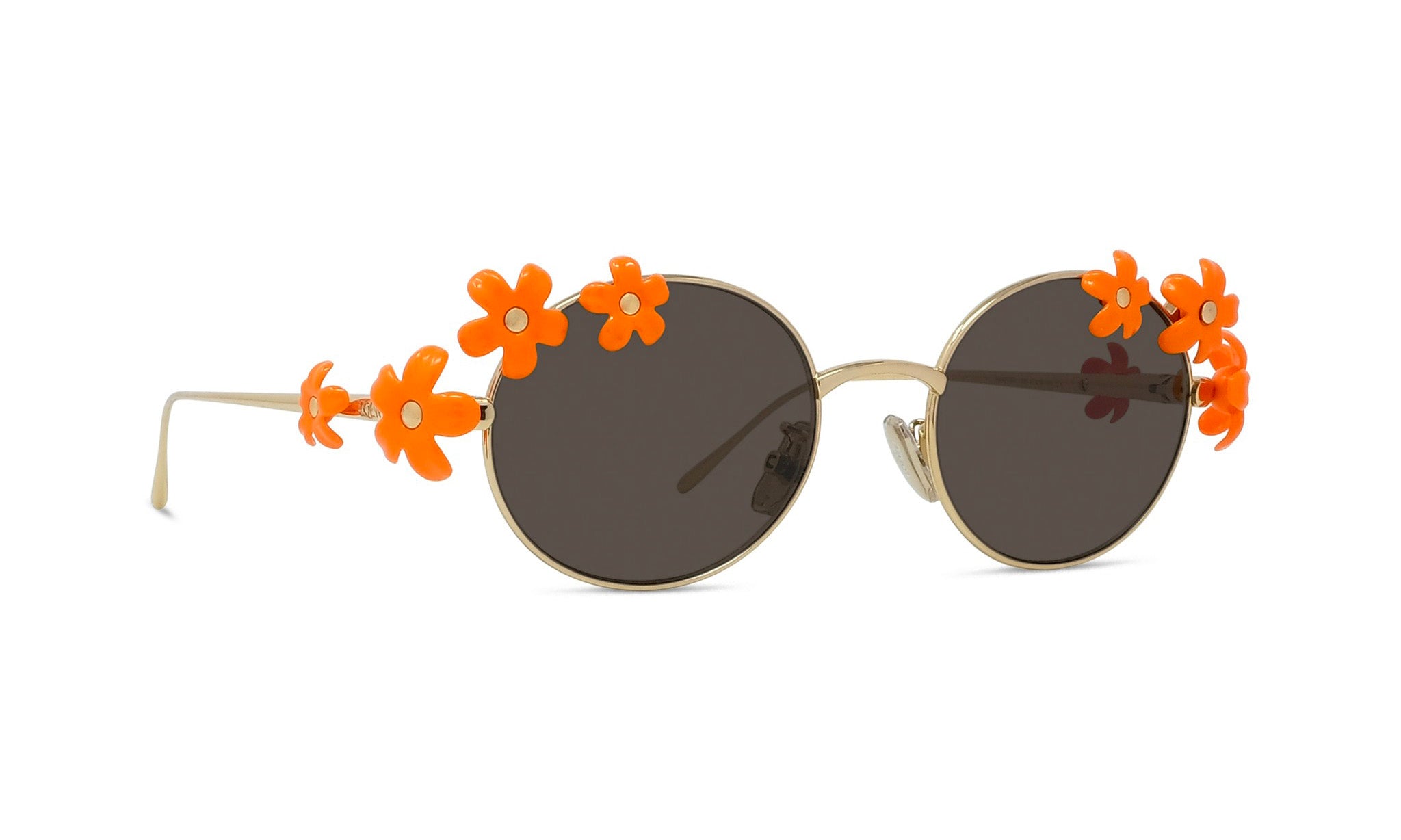 A pair of round sunglasses with a gold frame and dark lenses, adorned with orange flower-shaped embellishments on the sides.