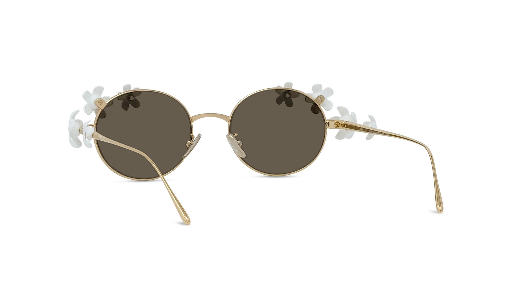 A pair of round sunglasses with dark lenses and gold frames adorned with white flower-shaped embellishments.
