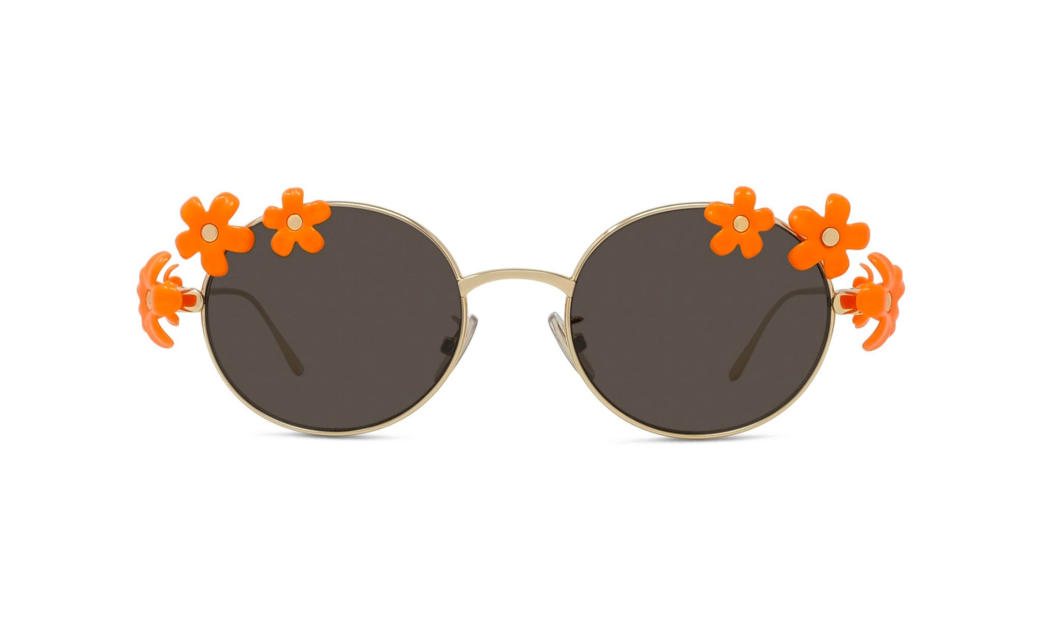 A pair of round sunglasses with dark lenses and orange flower decorations on the sides.