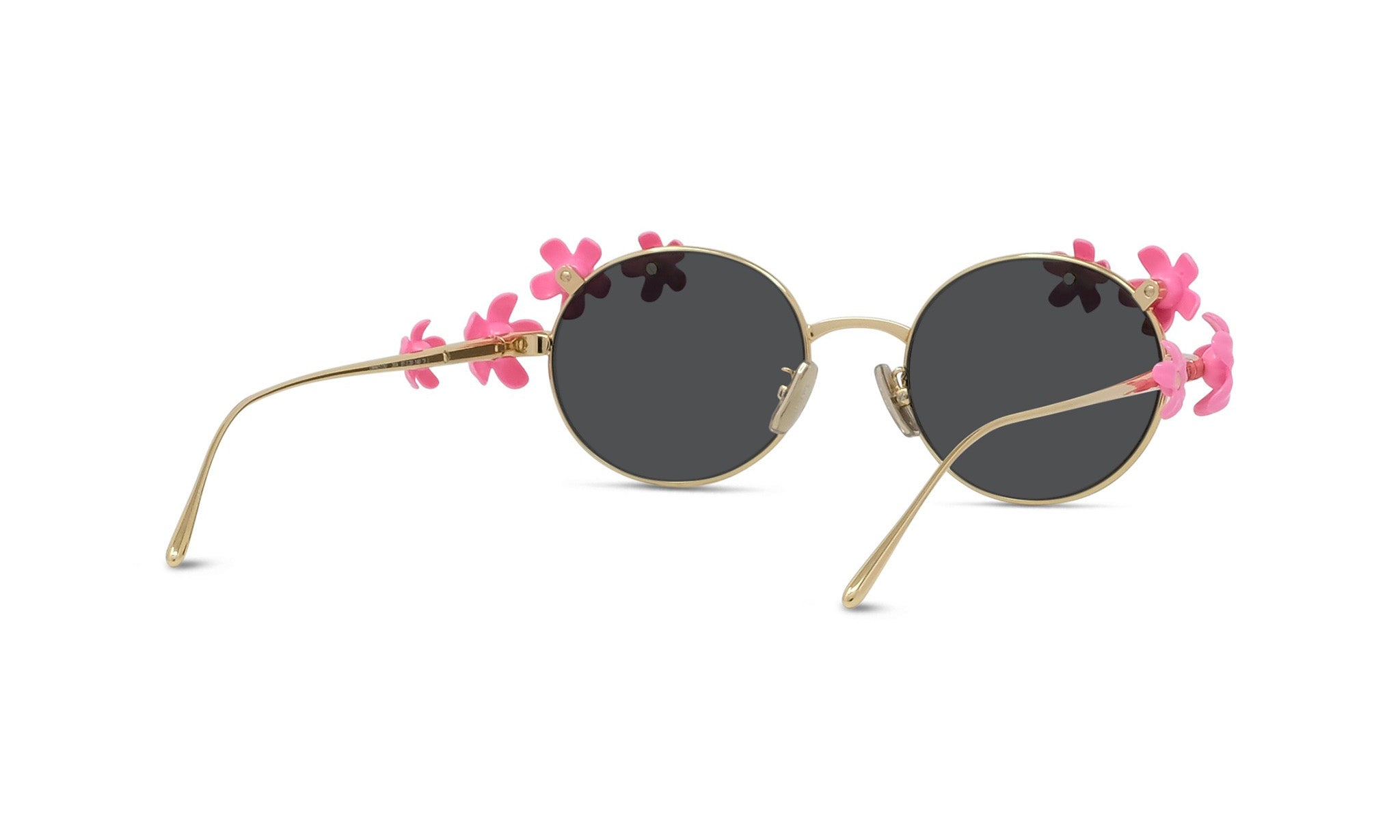 A pair of round sunglasses with gold frames and dark lenses, adorned with pink flowers on the sides.