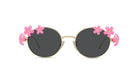 A pair of round sunglasses with black lenses and gold frames, adorned with pink flower decorations on the sides.