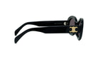 A pair of black sunglasses with a gold logo on the frame.
