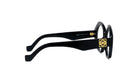 A pair of black-framed glasses with a gold-colored logo on the side.