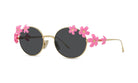 A pair of round sunglasses with a gold frame and dark lenses, adorned with pink flower embellishments on the temples and the sides.