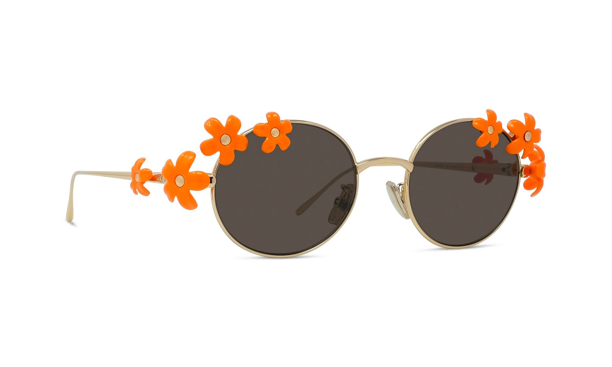 A pair of round sunglasses with a gold frame and dark lenses, adorned with orange flower-shaped embellishments on the sides.