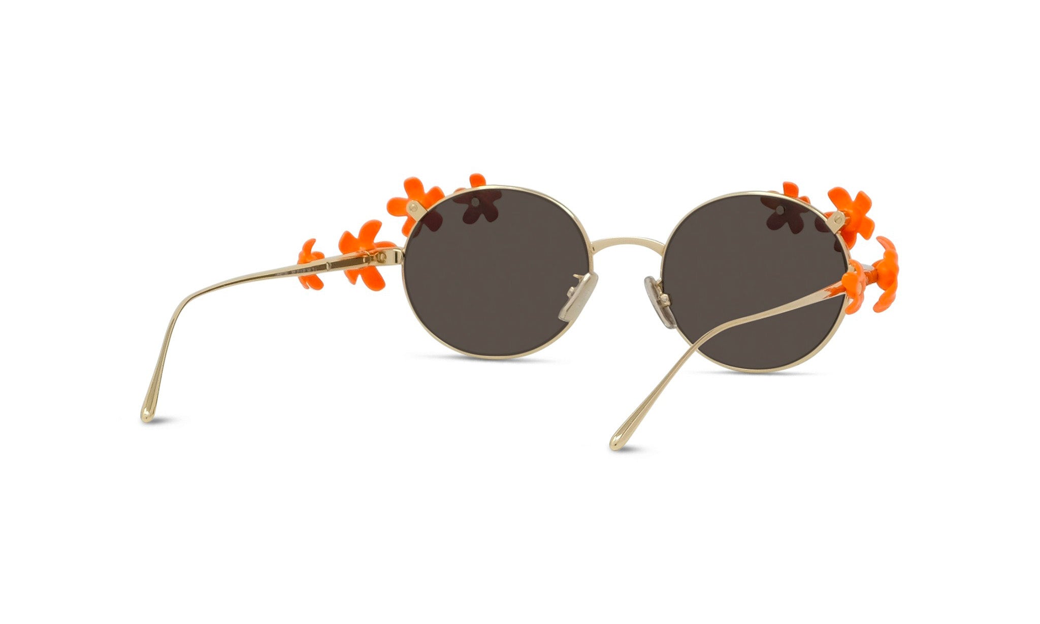 A pair of round sunglasses with a gold frame and dark lenses, adorned with orange flower-shaped embellishments on the sides.