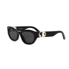 A pair of black sunglasses with a gold-colored logo on the frame.