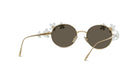 A pair of round, gold-colored sunglasses with dark lenses and white flower-shaped embellishments on the temples.